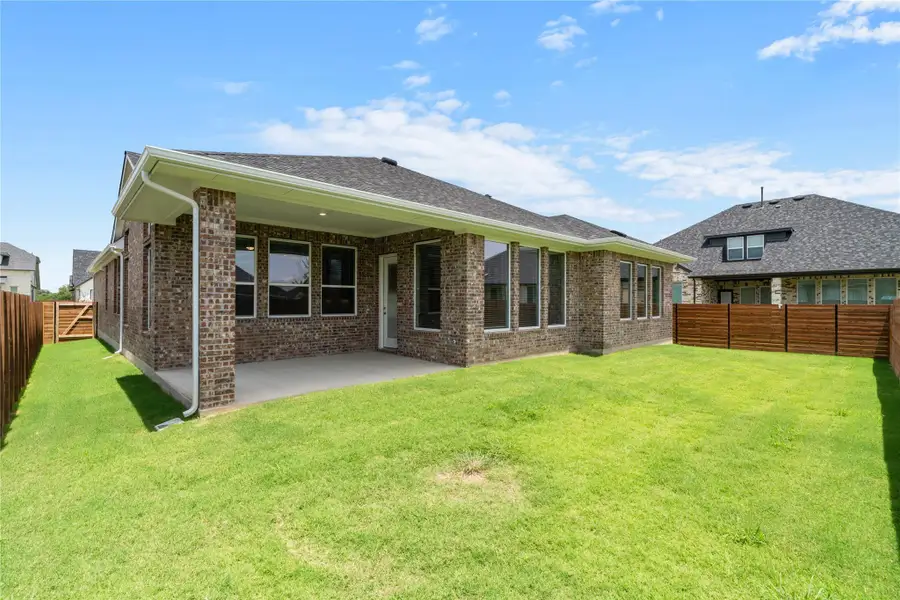 A well-maintained lawn stretches out to a brick home with a covered patio. A well-maintained lawn stretches out to a brick home with a covered patio.