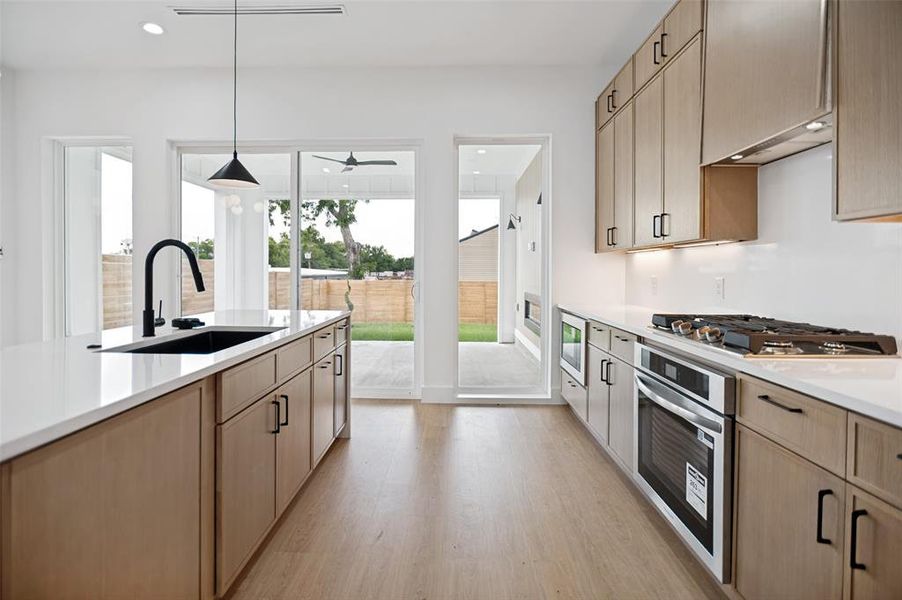 Modern kitchen featuring wood-finish cabinetry, white countertops, and stainless steel appliances