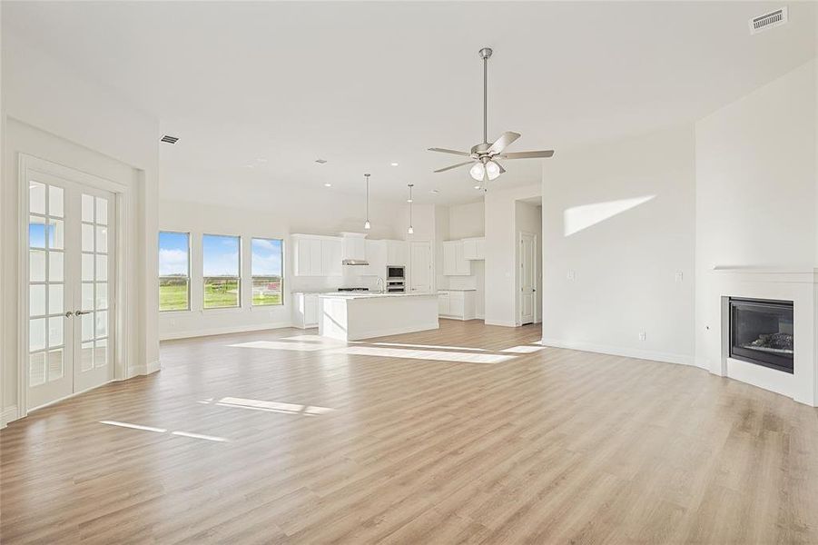 Unfurnished living room featuring french doors, light wood-type flooring, and ceiling fan