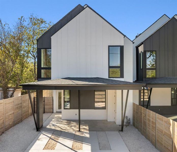 Rear view of house with a fenced backyard, board and batten siding, and roof with shingles