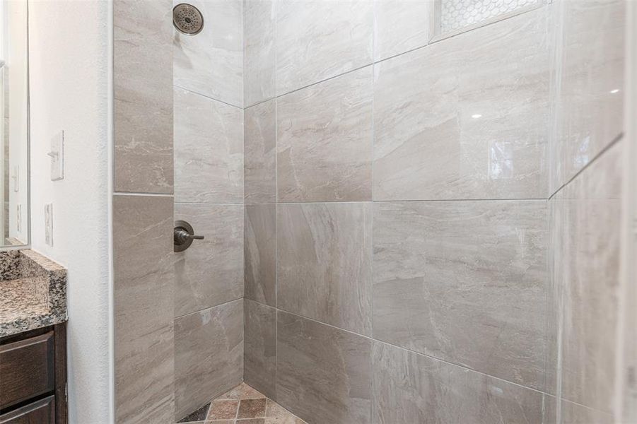 Full bathroom featuring tiled shower and vanity