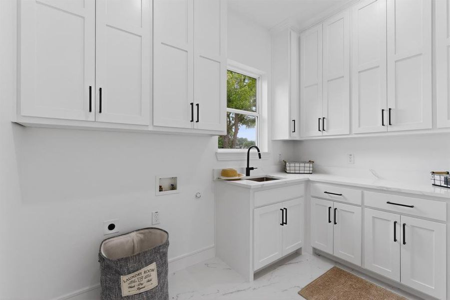 Dedicated laundry room featuring white shaker-style cabinetry with black hardware, white countertops, and a utility sink with a black gooseneck faucet