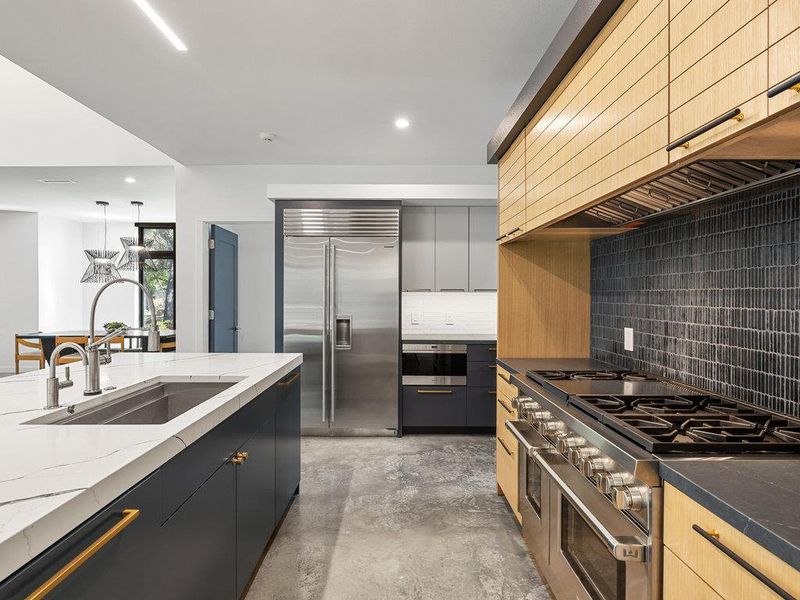 Kitchen with premium range hood, high end appliances, finished concrete floors, dark stone countertops, and recessed lighting