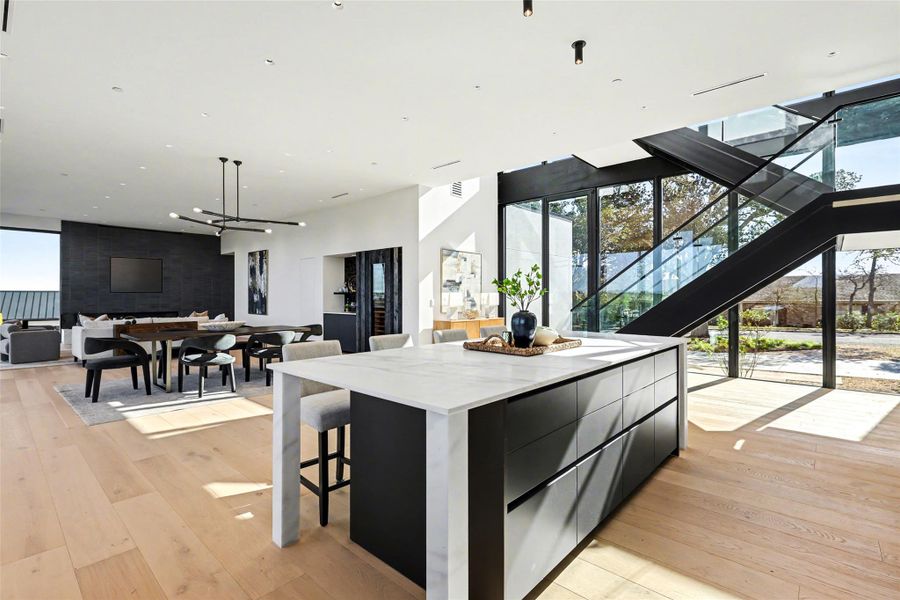 Kitchen with dark cabinets, a wall of windows, a kitchen island, modern cabinets, and a kitchen breakfast bar