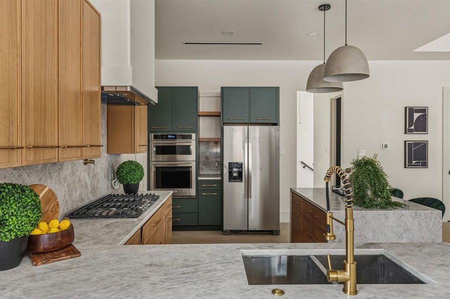 Kitchen with stainless steel appliances, tasteful backsplash, pendant lighting, and custom range hood