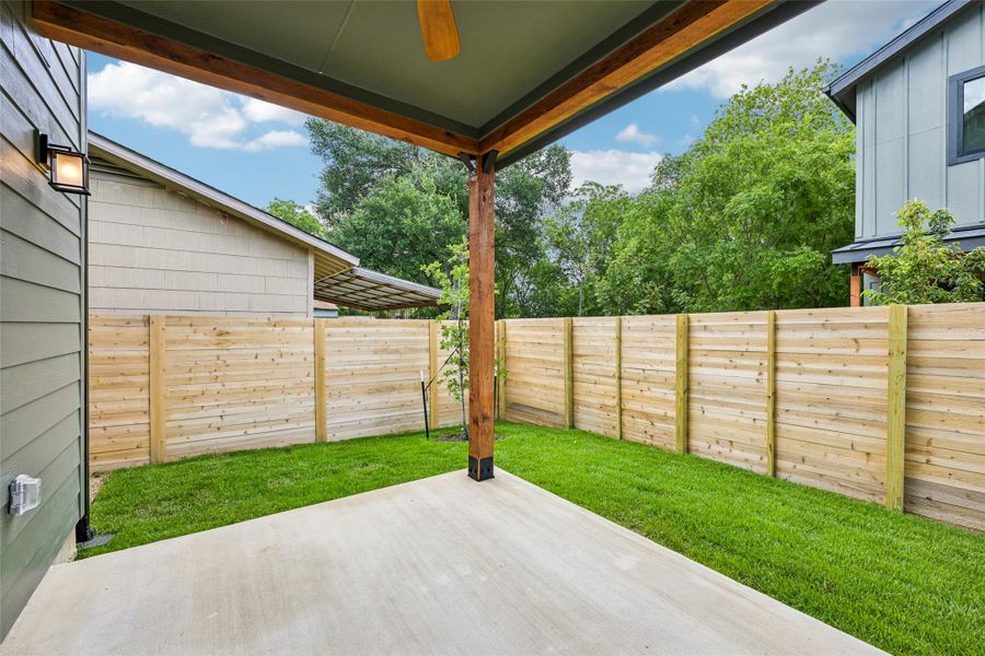 A private yard features a concrete patio and a newly installed cedar wood fence.