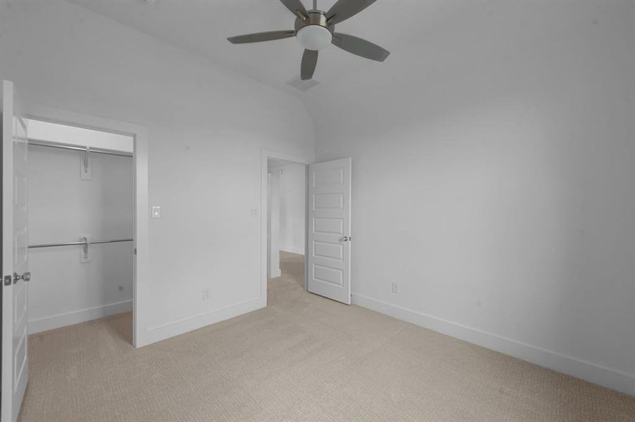 Unfurnished bedroom with lofted ceiling, light colored carpet, a ceiling fan, baseboards, and a closet