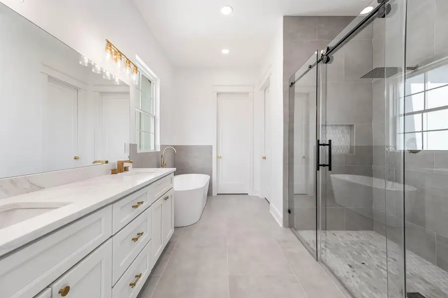 Spacious primary bathroom featuring a double vanity, freestanding soaking tub, and a large walk-in shower with glass doors.