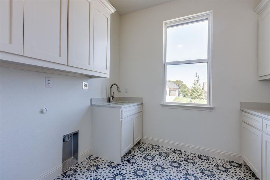 Laundry room featuring cabinets, sink, hookup for an electric dryer, and a wealth of natural light