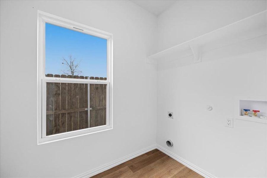 Laundry room with built-in shelving for storage and natural light. Dedicated utility space with water heater and functional layout.