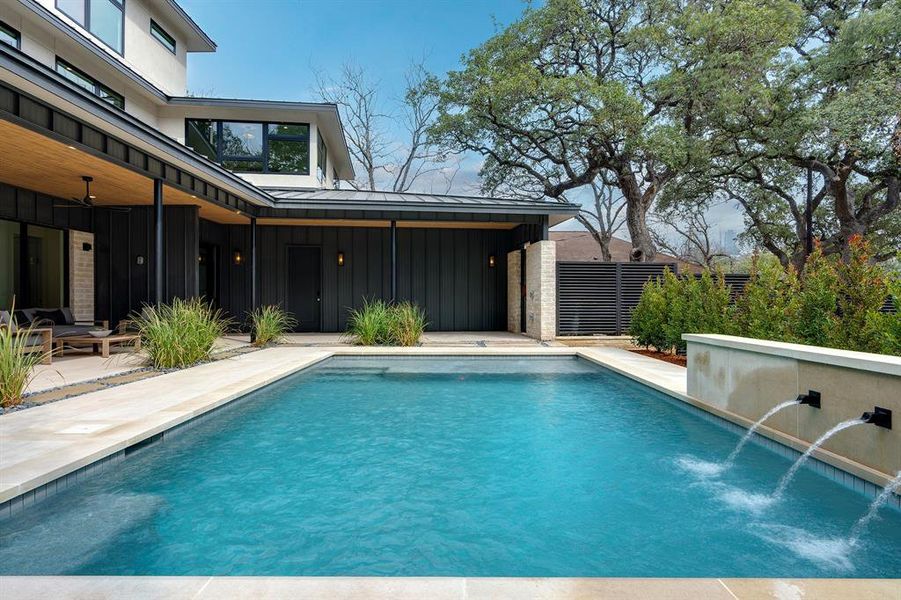 The pool is the heart of the outdoor space with a custom water feature, all just steps from the covered patio and main living areas.