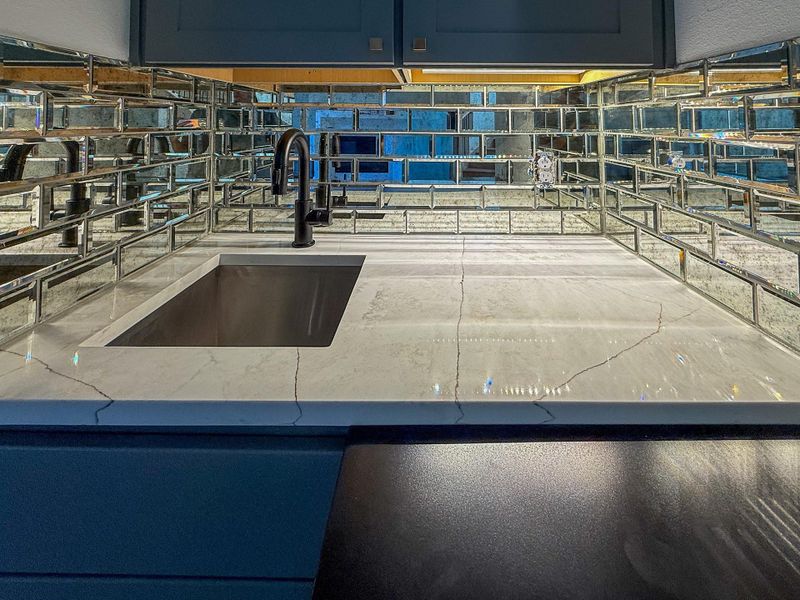A distinctive mirrored backsplash elevates this wet bar, conveniently located just off the living area and perfect for entertaining.