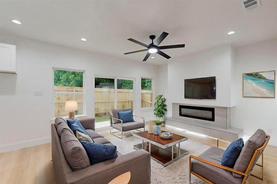 Living room with wood finished floors, recessed lighting, a glass covered fireplace, and ceiling fan Living room with wood finished floors, recessed lighting, a glass covered fireplace, and ceiling fan