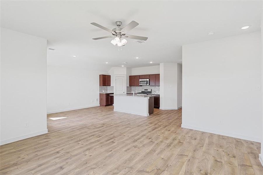 Unfurnished living room with ceiling fan and light wood-type flooring