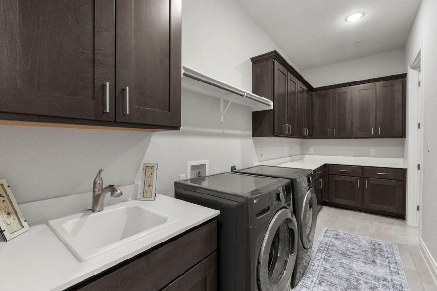 Ample cabinetry, a utility sink, and a clothes rack elevate the convenience of this organized laundry area.
