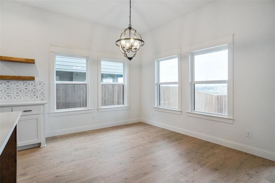 Unfurnished dining area featuring light wood finished floors and a chandelier
