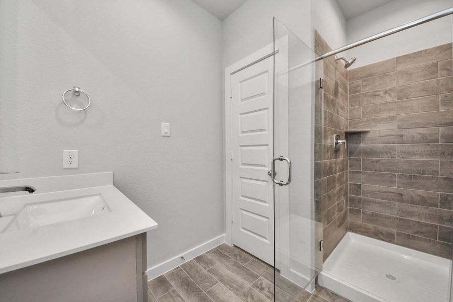 Guest bathroom, featuring a walk-in shower with tile surround. Sample photo of completed home with similar floor plan. Actual colors and selections may vary.