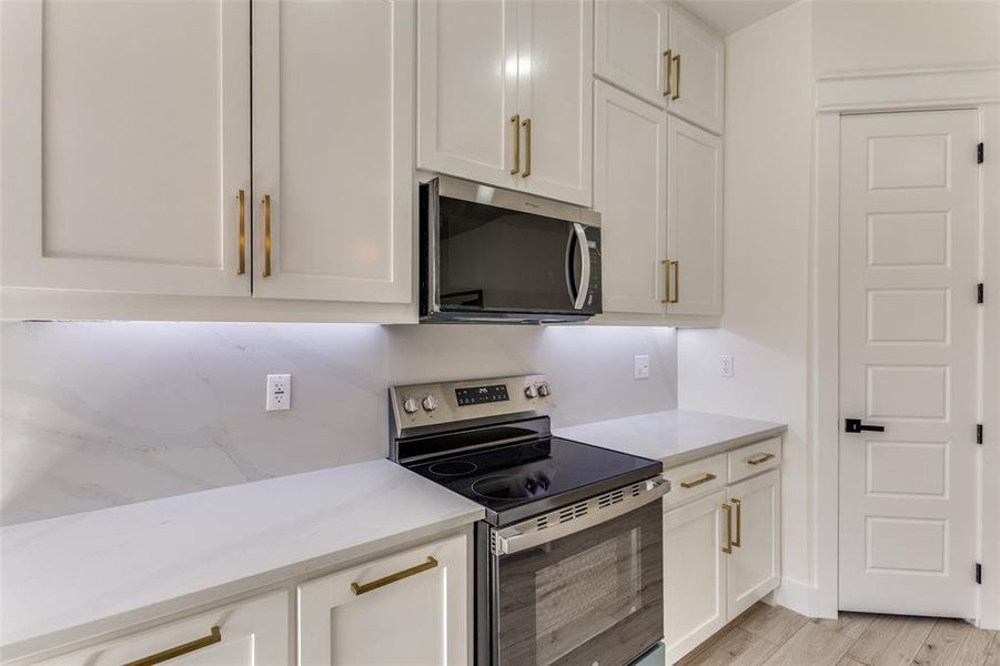 Kitchen featuring appliances with stainless steel finishes, white cabinets, and light wood finished floors