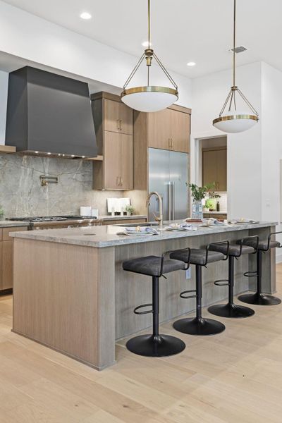 Kitchen with tasteful backsplash, a large island with sink, a kitchen bar, decorative light fixtures, and recessed lighting