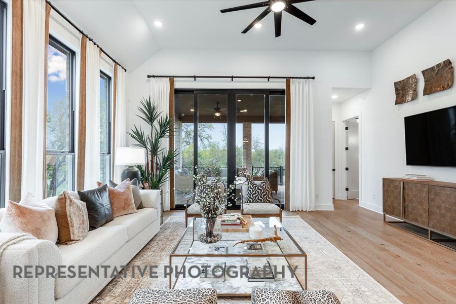 Living area featuring recessed lighting, lofted ceiling, wood finished floors, baseboards, and ceiling fan Living area featuring recessed lighting, lofted ceiling, wood finished floors, baseboards, and ceiling fan