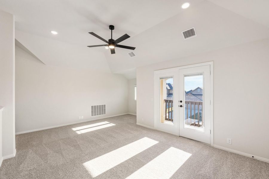 Empty room with vaulted ceiling, ceiling fan, carpet flooring, and French doors leading to a balcony Empty room with vaulted ceiling, ceiling fan, carpet flooring, and French doors leading to a balcony