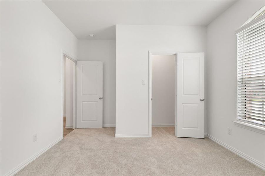 Unfurnished bedroom with light colored carpet, a spacious closet, and a closet