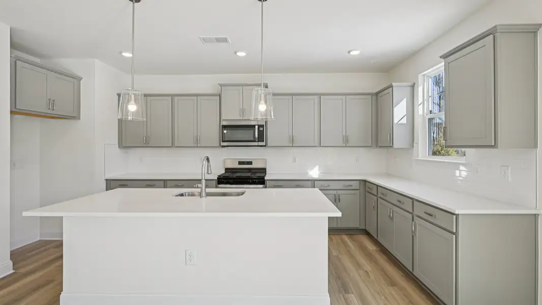 Wagener home plan spacious kitchen with island, tile backsplash, pendant lights, ample counter space and cabinetry Wagener home plan spacious kitchen with island, tile backsplash, pendant lights, ample counter space and cabinetry