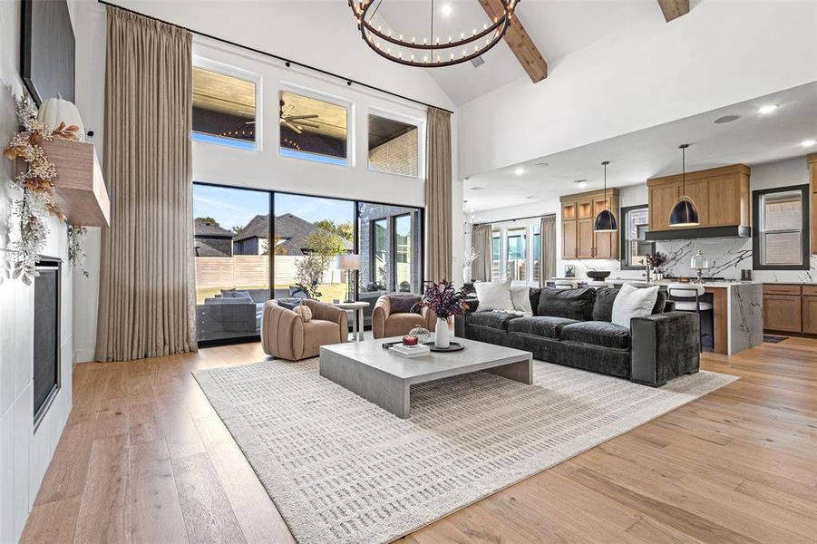 Living area with beamed ceiling, healthy amount of natural light, a chandelier, light wood-style flooring, and high vaulted ceiling Living area with beamed ceiling, healthy amount of natural light, a chandelier, light wood-style flooring, and high vaulted ceiling