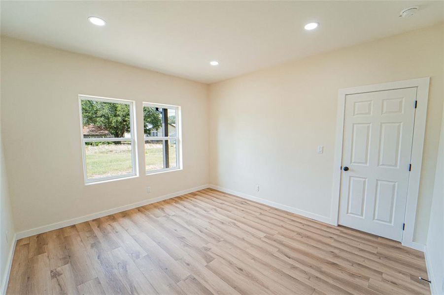 Bed room featuring wood-finish flooring, recessed lighting, and a paneled interior door with black hardware
