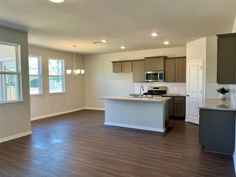 Kitchen with light stone counters, a chandelier, stainless steel appliances, and dark wood-style floors
