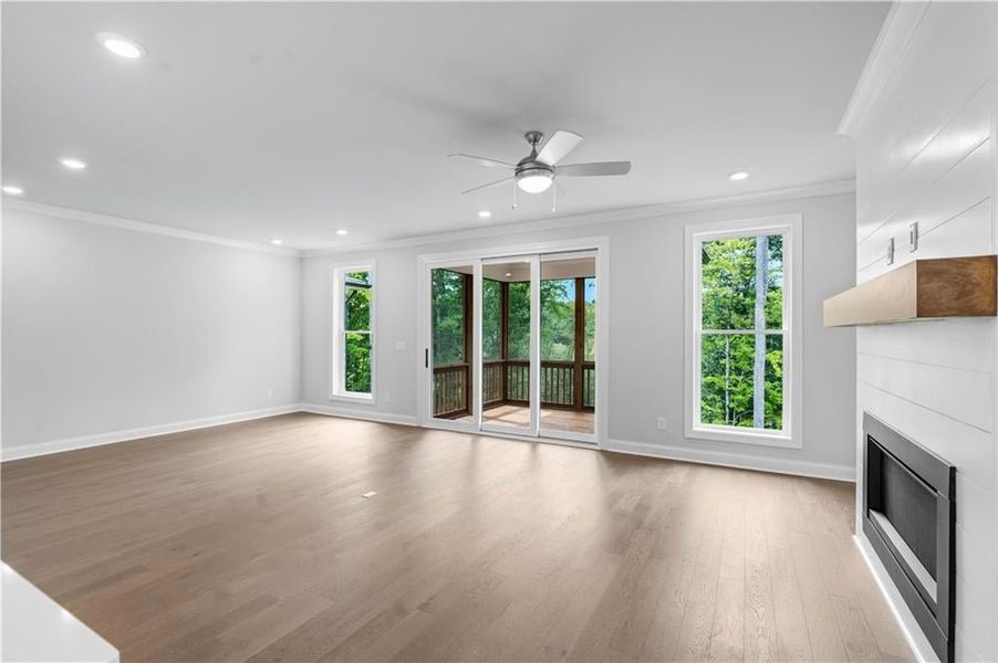 Unfurnished living room with ornamental molding, a glass covered fireplace, light wood-type flooring, recessed lighting, and a ceiling fan Unfurnished living room with ornamental molding, a glass covered fireplace, light wood-type flooring, recessed lighting, and a ceiling fan