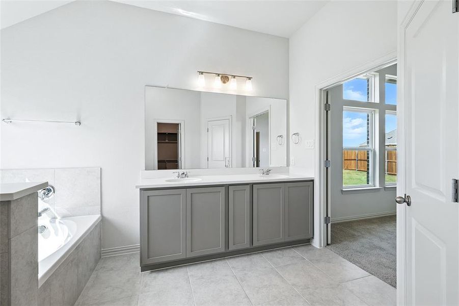 Full bathroom with double vanity, a bath, and light tile patterned floors Full bathroom with double vanity, a bath, and light tile patterned floors