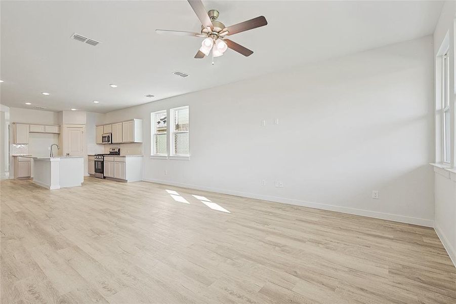 Unfurnished living room featuring sink, ceiling fan, and light hardwood / wood-style flooring