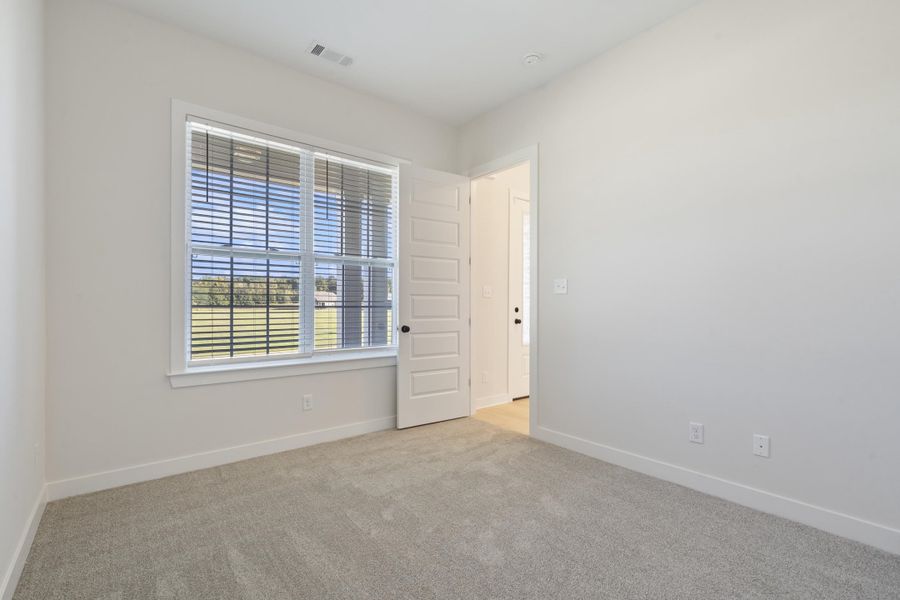 Carpeted flooring, white walls, white trim, white door with black hardware, and a window with horizontal blinds