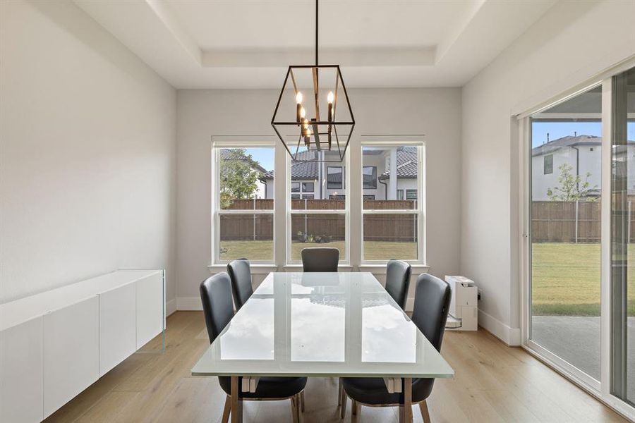 Dining room featuring light wood finished floors, a tray ceiling, and a chandelier