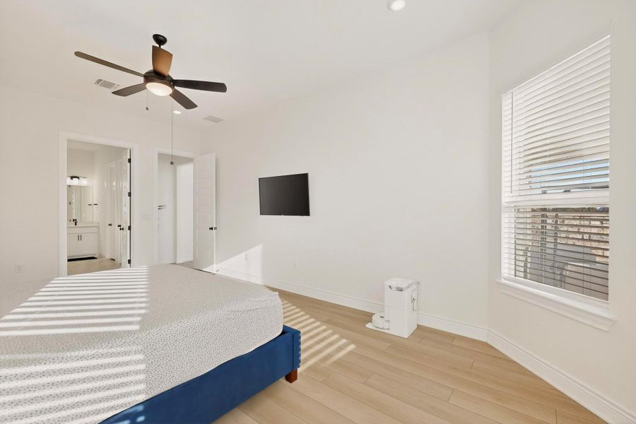 Bedroom with wood finished floors, a ceiling fan, and ensuite bathroom