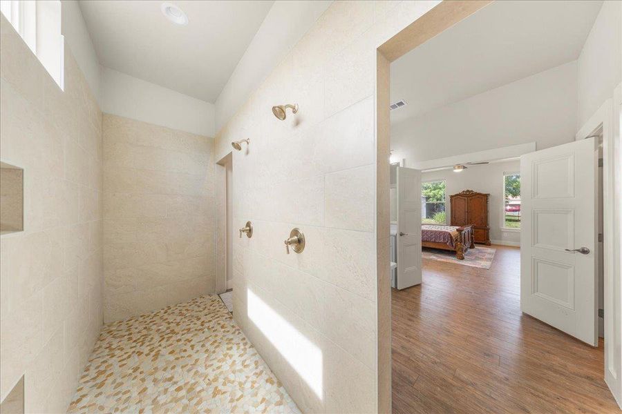 Ensuite bathroom with a walk in shower, wood finished floors, tile walls, and ceiling fan Ensuite bathroom with a walk in shower, wood finished floors, tile walls, and ceiling fan