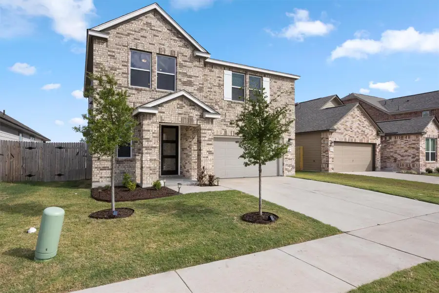 Traditional home with driveway, brick siding, and a garage
