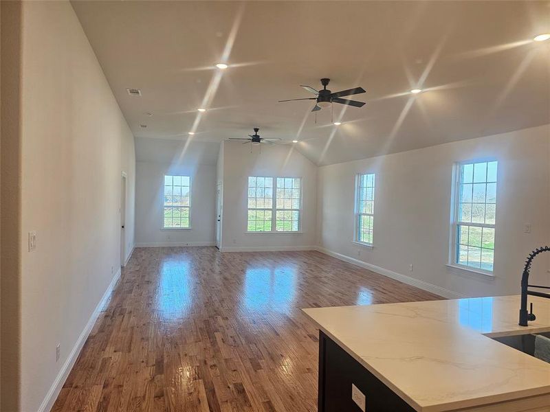 Unfurnished living room with ceiling fan, lofted ceiling, sink, and light hardwood / wood-style flooring