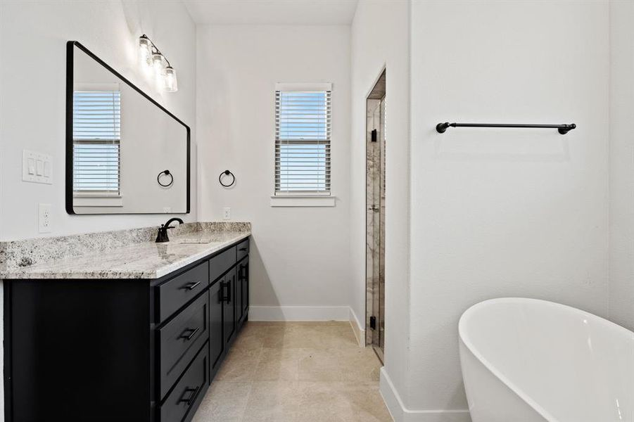 Bathroom with a freestanding tub, baseboards, a stall shower, and vanity