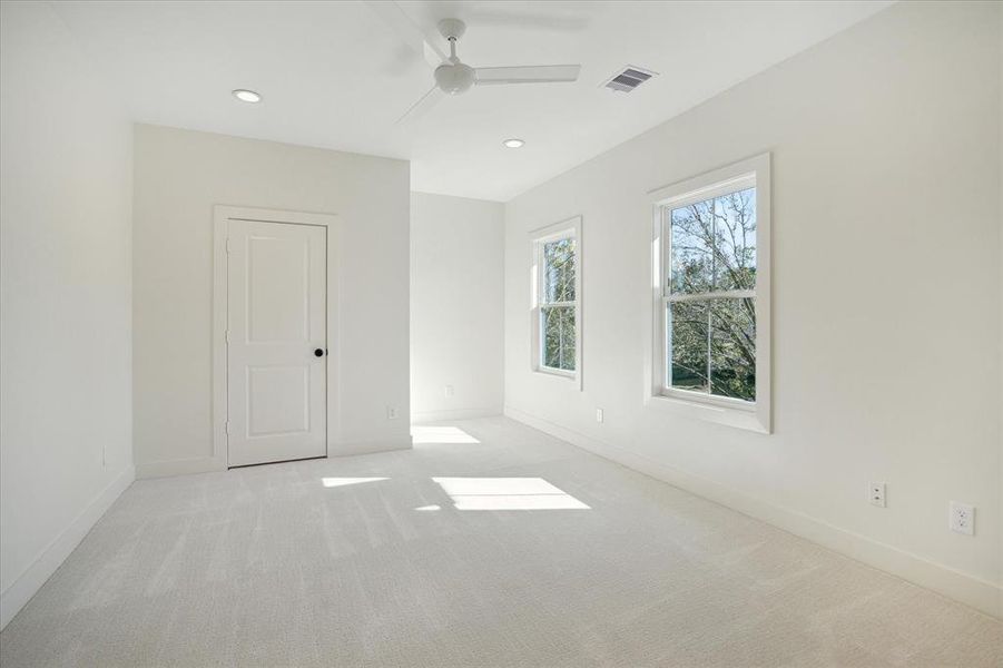 Bright and spacious, this secondary bedroom features soft carpeting and a neutral color scheme, offering a cozy and versatile space. Large windows frame serene outdoor views, bringing in ample natural light. A well-sized closet provides ample storage, making this room ideal for family members, guests, or a personalized workspace. Clean lines and understated finishes create a fresh and inviting atmosphere.