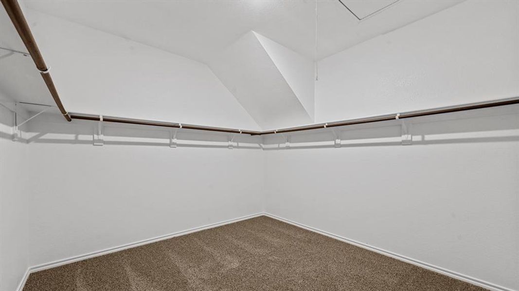 Spacious closet featuring white walls, a vaulted ceiling, brown carpet flooring, and integrated clothing rods Spacious closet featuring white walls, a vaulted ceiling, brown carpet flooring, and integrated clothing rods