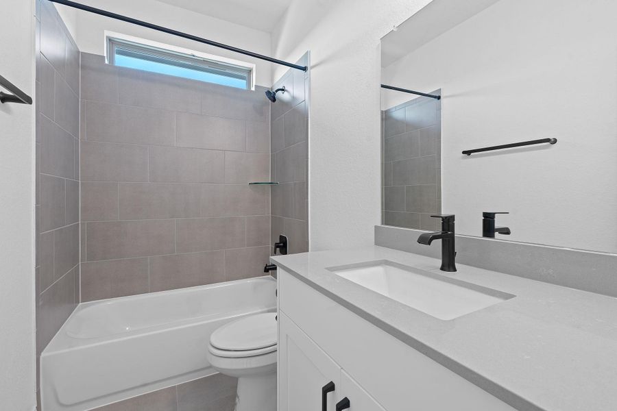 Full bathroom featuring shower / bath combination, vanity, and dark tile patterned flooring Full bathroom featuring shower / bath combination, vanity, and dark tile patterned flooring