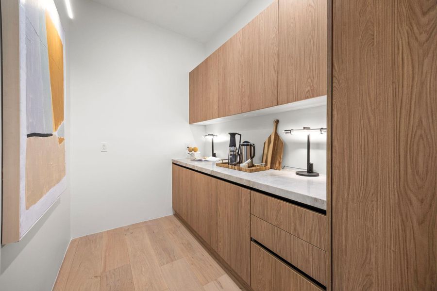 Behind the flush wood grain hidden door lies the Butlers pantry w/ additional counter & cabinet space.