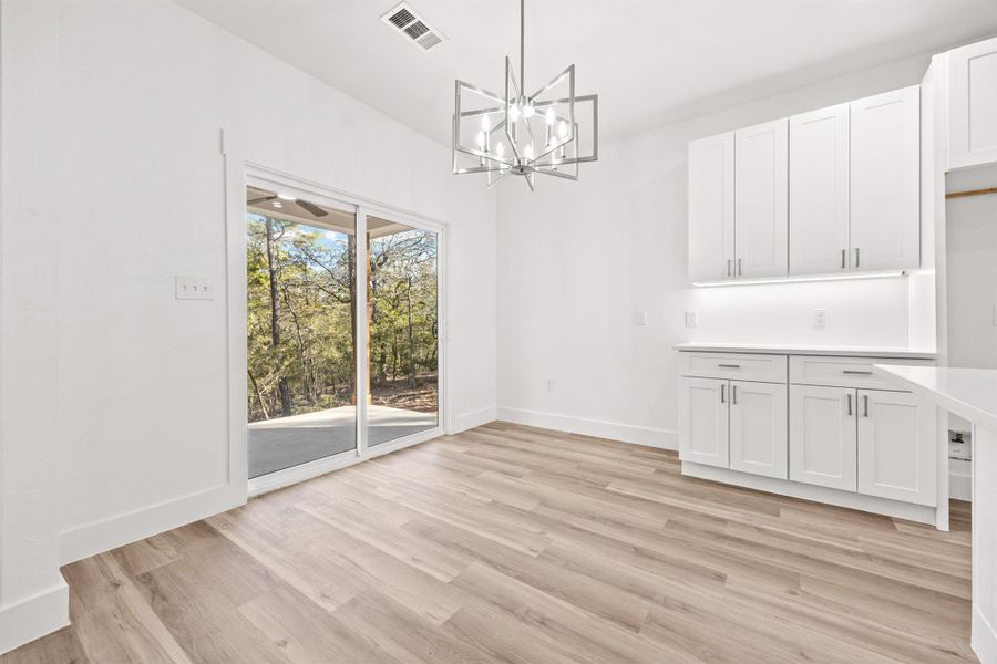 Unfurnished dining area featuring hanging lights and light wood-style floors