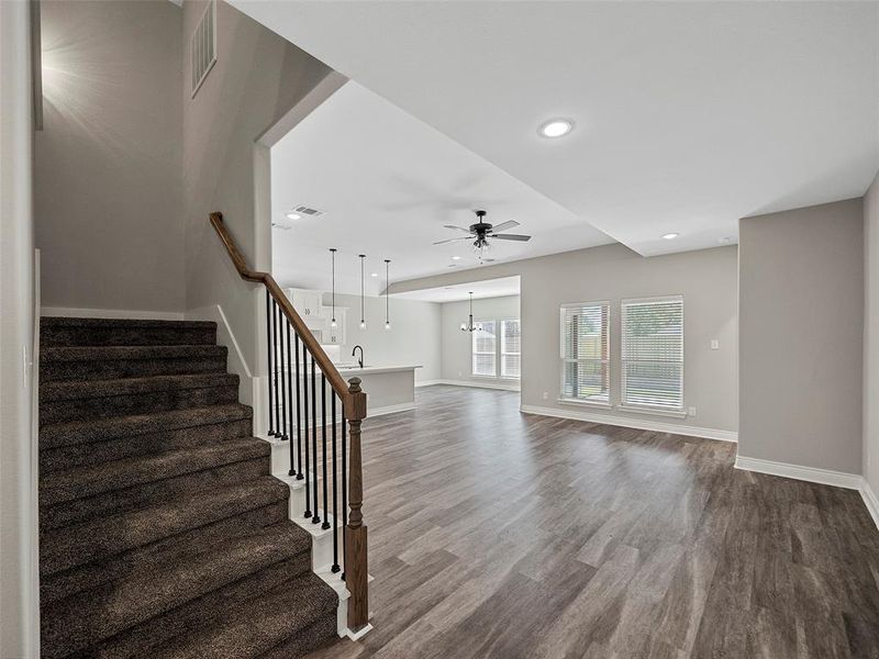 Unfurnished living room featuring stairway, wood finished floors, recessed lighting, a ceiling fan, and a chandelier Unfurnished living room featuring stairway, wood finished floors, recessed lighting, a ceiling fan, and a chandelier