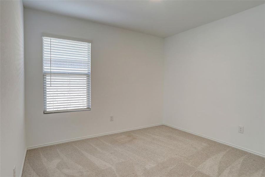 Empty room with light colored carpet and baseboards