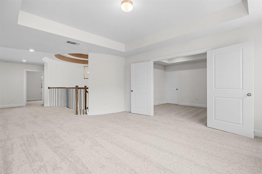 Carpeted spare room featuring a tray ceiling and baseboards Carpeted spare room featuring a tray ceiling and baseboards