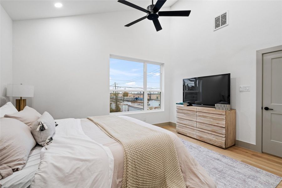Natural light pours through the oversized windows, enhancing the clean lines and calming tones of this spacious primary suite. Elevated by vaulted ceilings, neutral trim, and wide-plank flooring, it’s the perfect balance of comfort and modern design.