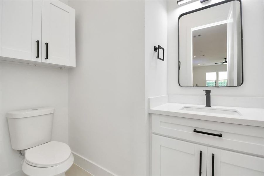 The half bathroom, situated on the 2nd floor, is adorned with contemporary finishes. white cabinets paired with a light countertop, custom wall paint, and a sleek faucet combine to create a bright and inviting space.